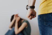 Man Clenching Fist Near a Woman Covering Face While Sitting