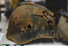 rusty soldier helmet with holes on white surface
