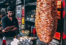 man in black button up shirt standing in front of food display
