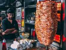 man in black button up shirt standing in front of food display