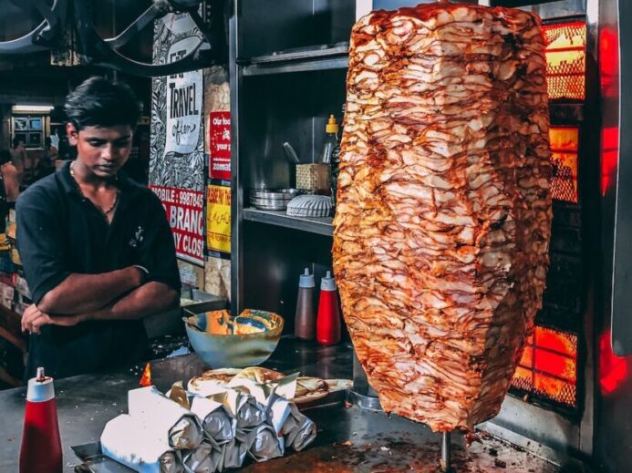 man in black button up shirt standing in front of food display