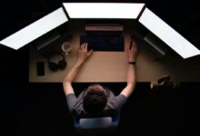 man facing three computer monitors while sitting