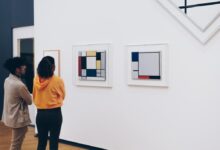 man and woman standing facing painting inside room