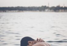 topless man beside body of water