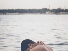topless man beside body of water