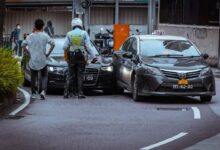 man in white and black stripe shirt and black pants standing beside black car during daytime