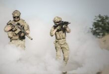 Men Holding Rifle While Walking Through Smoke Grenade