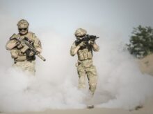 Men Holding Rifle While Walking Through Smoke Grenade