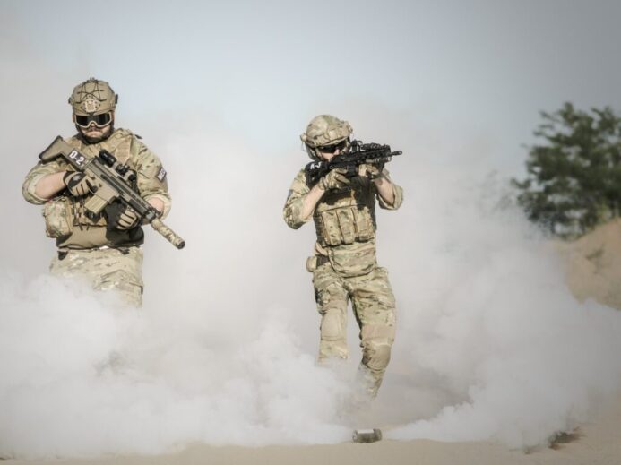 Men Holding Rifle While Walking Through Smoke Grenade