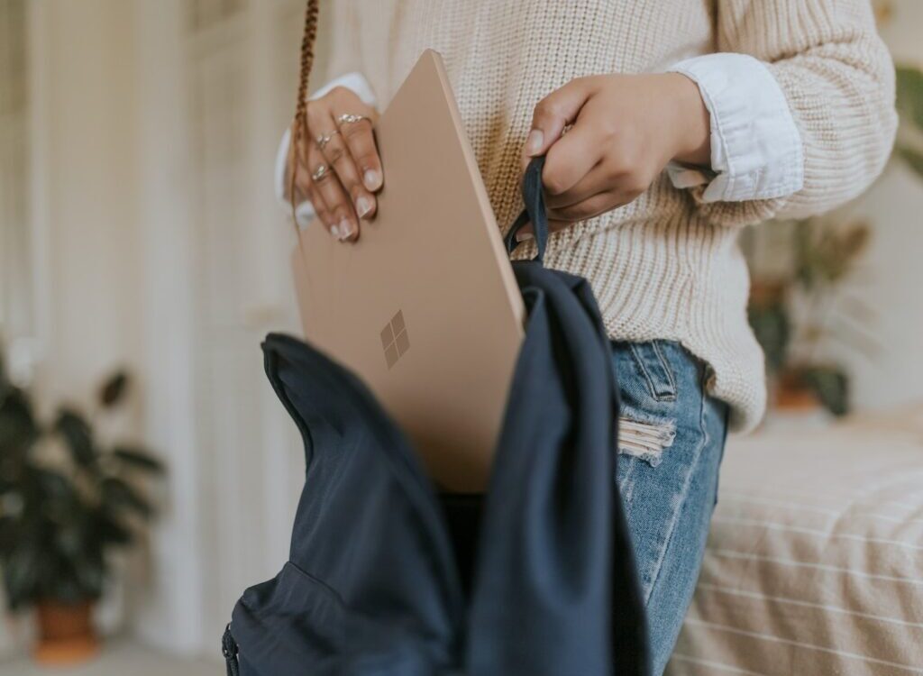 woman in blue denim jeans holding sandstone surface laptop