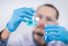 Person Holding Glass Flasks