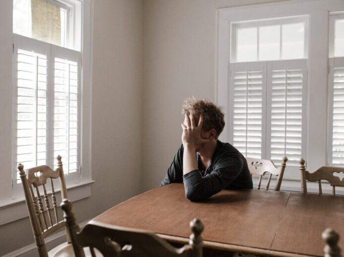 Photo of Man Leaning on Wooden Table