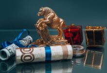 Golden ox figurine with small wrapped New Year presents composed with coins stack and rolled various banknotes