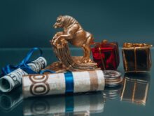 Golden ox figurine with small wrapped New Year presents composed with coins stack and rolled various banknotes