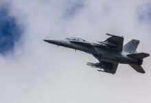 fighter jet flying under white clouds