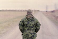 man in green camouflage uniform standing on road during daytime