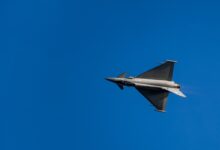 gray jet plane in mid air during daytime