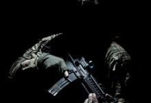 man in black and green camouflage suit holding rifle