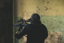 man in black jacket holding rifle
