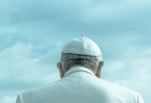person wearing white cap looking down under cloudy sky during daytime