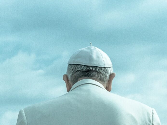 person wearing white cap looking down under cloudy sky during daytime