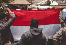 man in black leather jacket holding red flag