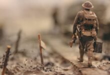 soldier walking on wooden pathway surrounded with barbwire selective focus photography