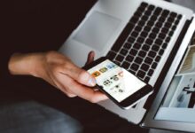person holding smartphone and laptop