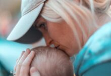 macro photography of woman kissing baby head