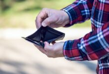 person in red blue and white plaid long sleeve shirt holding black leather bifold wallet