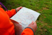 person in orange long sleeve shirt holding white printer paper