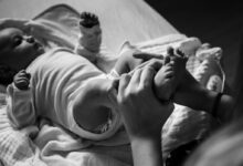 grayscale photo of baby lying on bed