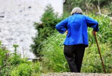 woman walking while holding walking cane