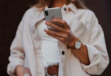 woman in white coat holding silver iphone 6