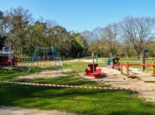 red and black playground surrounded by trees during daytime
