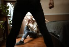 Woman in Black Pants and White Long Sleeve Shirt Lying on Brown Wooden Floor