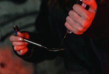 A Person Using Spoon and Syringe in Consuming Illegal Substance