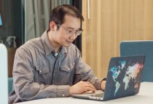 A Man in Gray Sleeves Using a Laptop