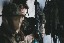 man in black helmet and black helmet holding rifle