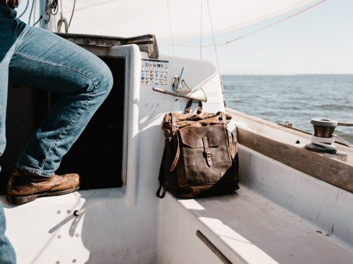person in blue denim jeans on yacht beside brown bag