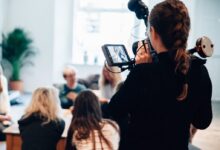 woman holding camera standing near people
