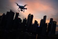 silhouette of quadcopter drone hovering near the city