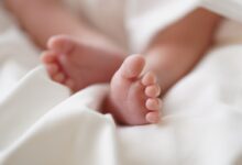 babys feet on white textile