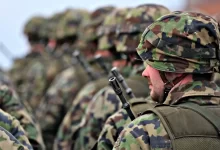 man in green and brown camouflage uniform holding black rifle