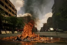 fire burning on the road with high rise buildings during daytime photography
