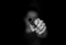 grayscale photography ofperson holding gun