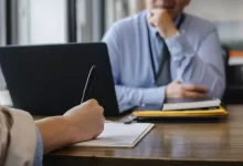 Crop anonymous female filling questionnaire when applying for job sitting in employer office