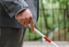 Person in Gray Suit Holding a Walking Stick