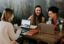 three people sitting in front of table laughing together