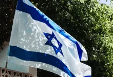 a flag flying in the wind with trees in the background